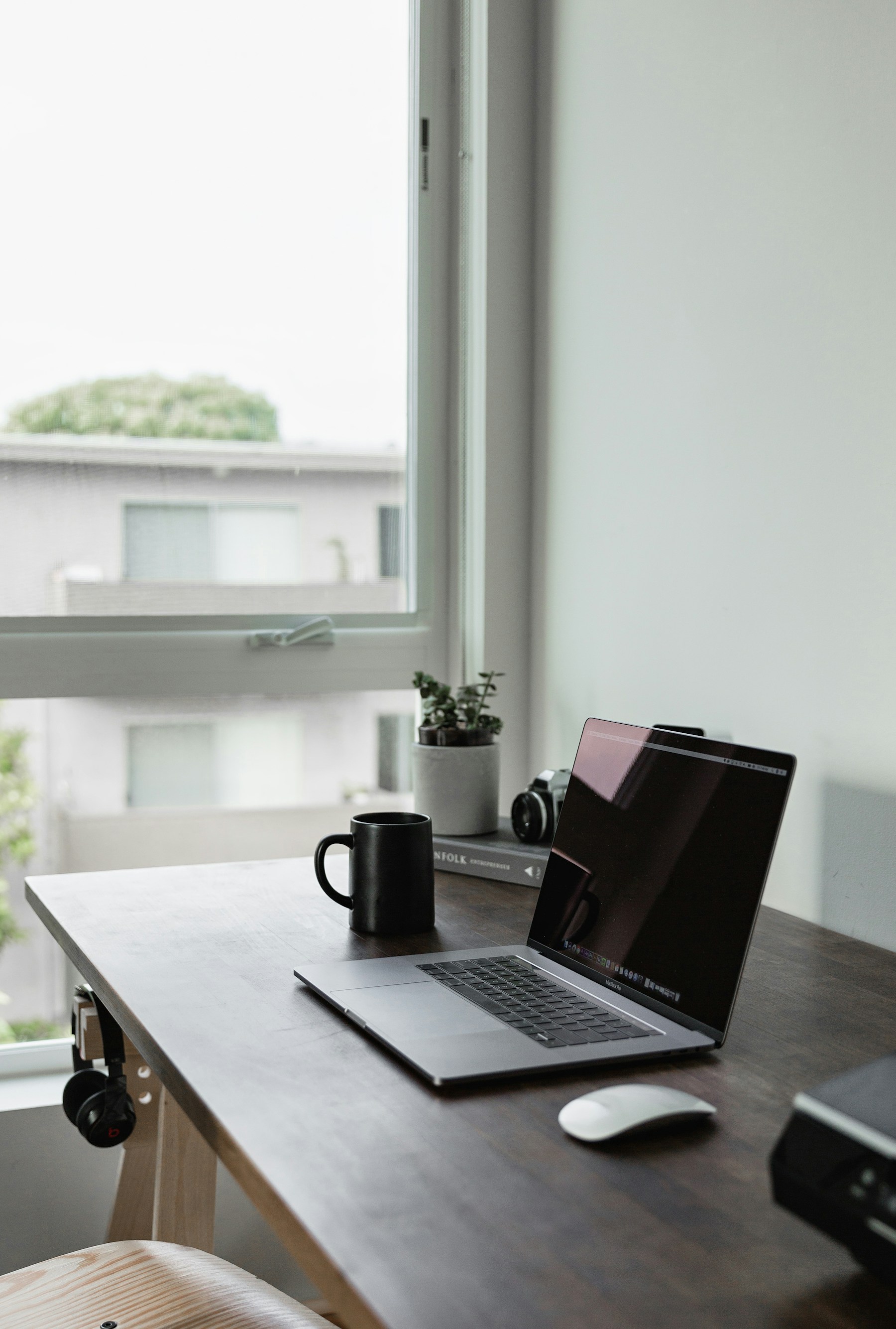 Laptop and notebook by a window, used as an editorial workspace image